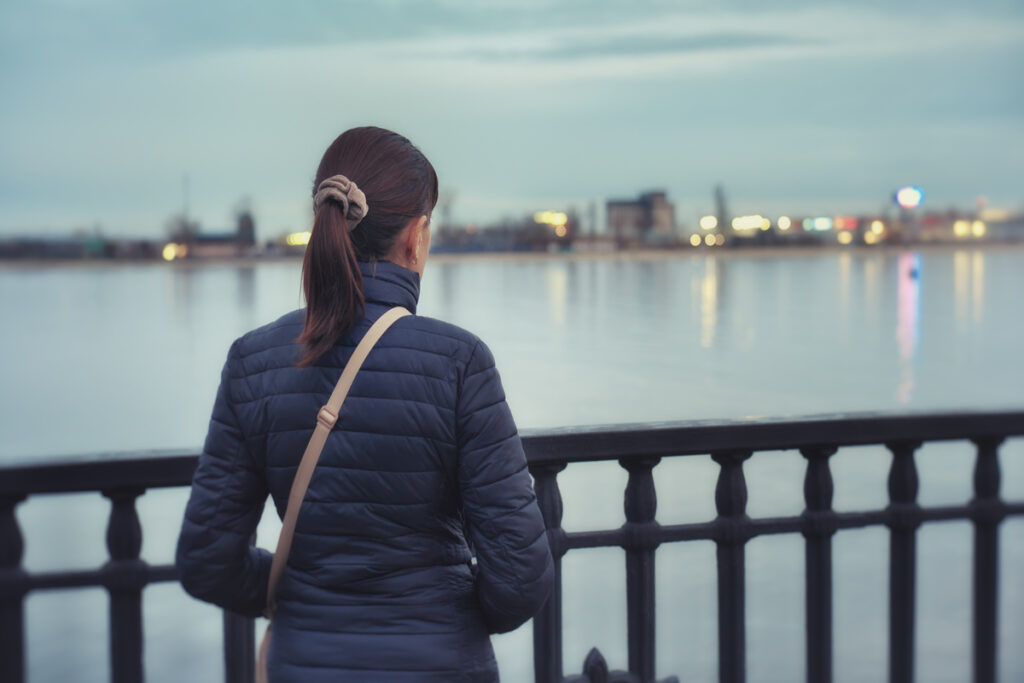 Женщина идёт по набережной вечером