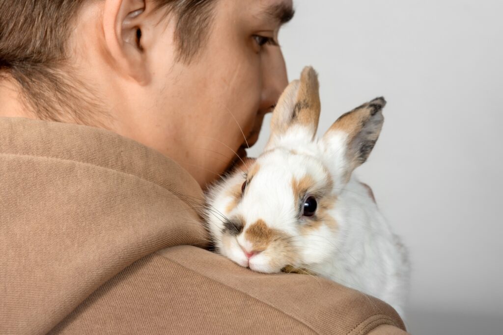 Молодой человек держит на руках маленького кролика