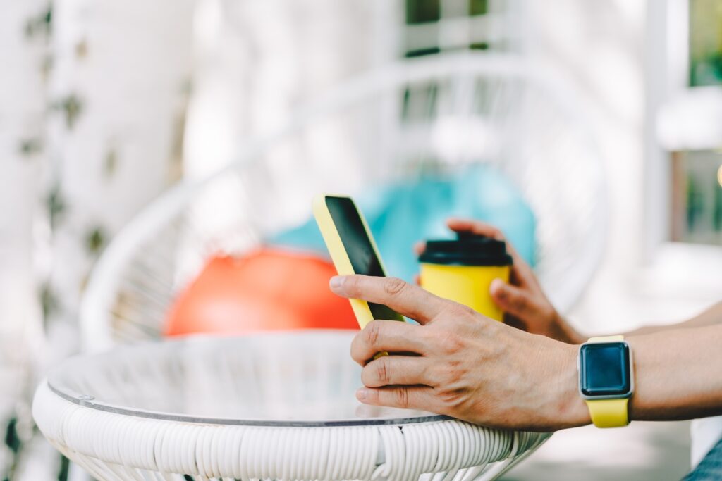 Женские руки с кофейной чашкой и мобильным телефоном