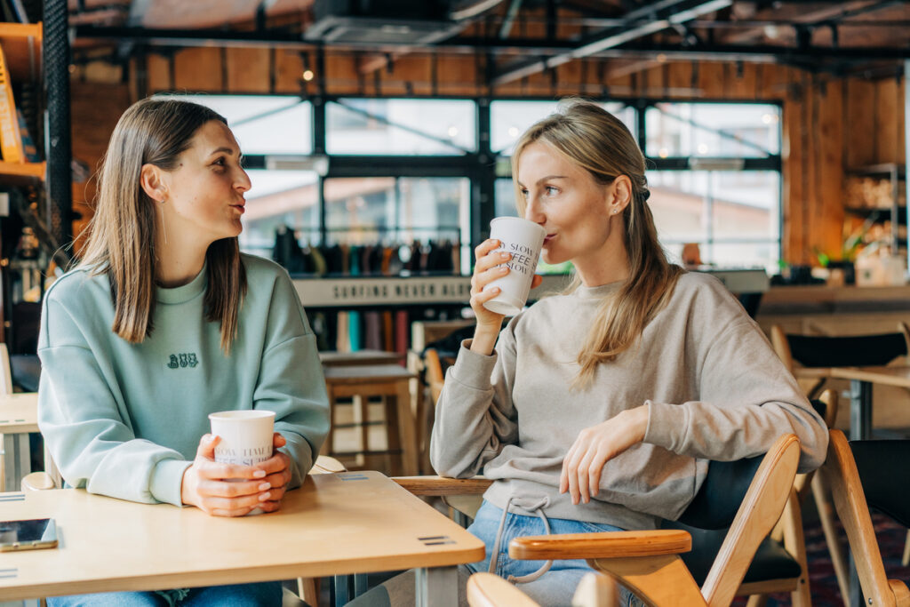 Две подруги пьют кофе в уютной кофейне
