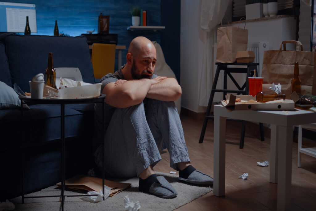 Мужчина в стрессе сидит на полу комнаты