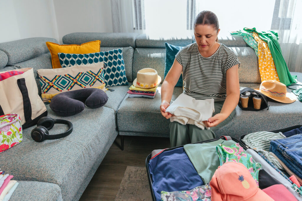 Женщина упаковывает одежду в чемодан