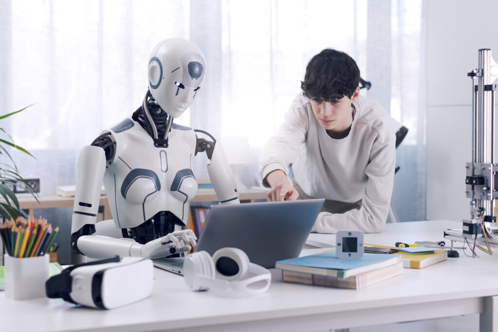 Парень работает на ноутбуке с роботом