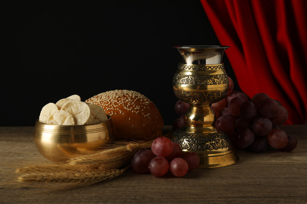 Хлеб, колосья, виноград и чашка на деревянном столе