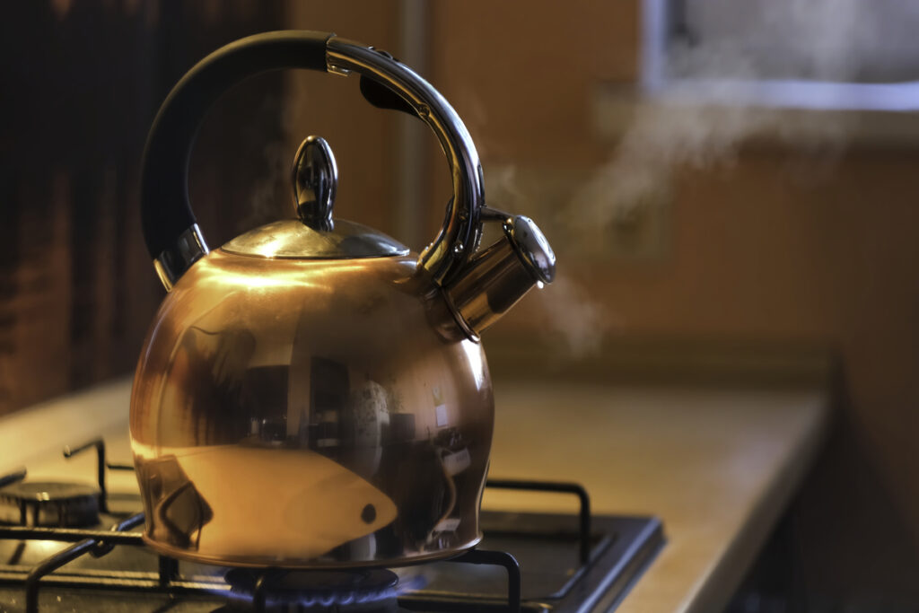 Металлический серебристый чайник на газовой плите