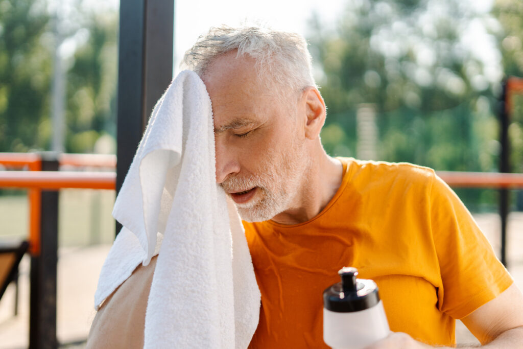 Пожилой мужчина вытирает лицо после тренировки
