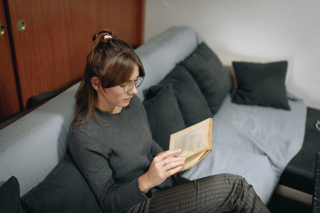 Молодая женщина отдыхает дома, читая книгу