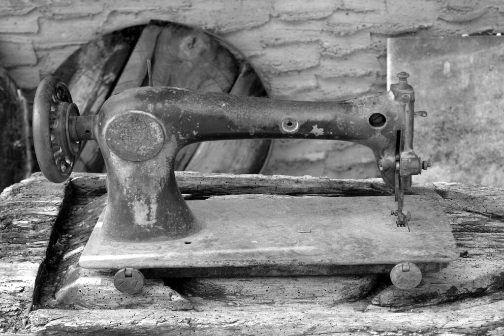 Старинная швейная машинка на столе из выветренного дерева
