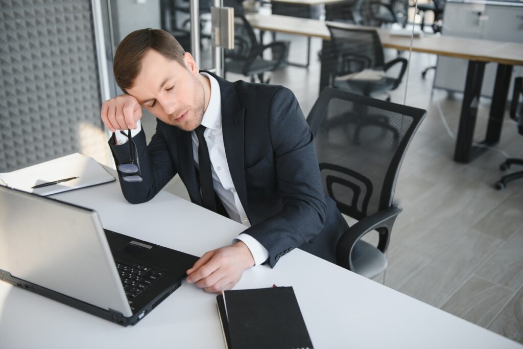 Уставший бизнесмен спит за рабочим столом в офисе