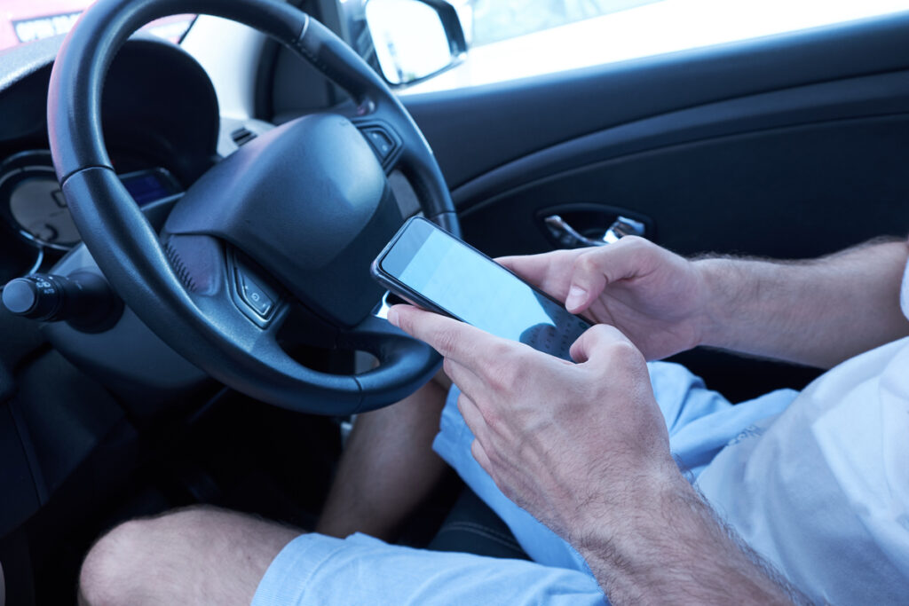 Мужчина сидит в машине с мобильным телефоном за рулем