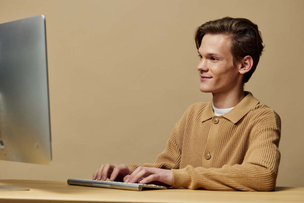 Молодой человек работает за компьютером дома