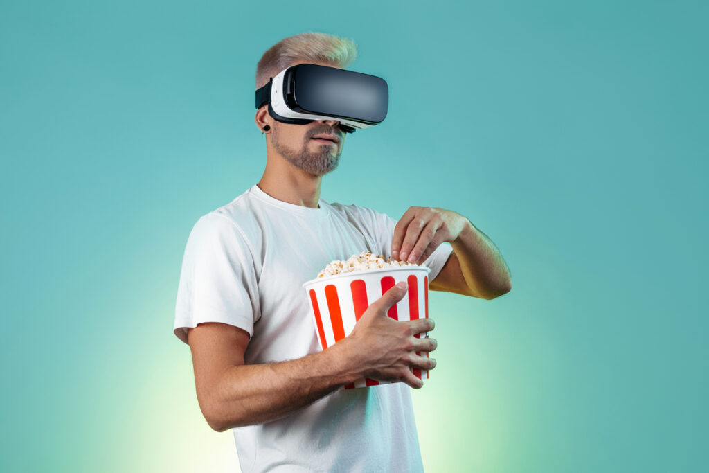 Мужчина в очках виртуальной реальности ест попкорн