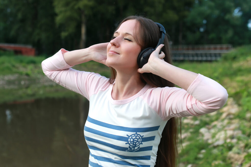 Женщина наслаждается музыкой в наушниках на природе