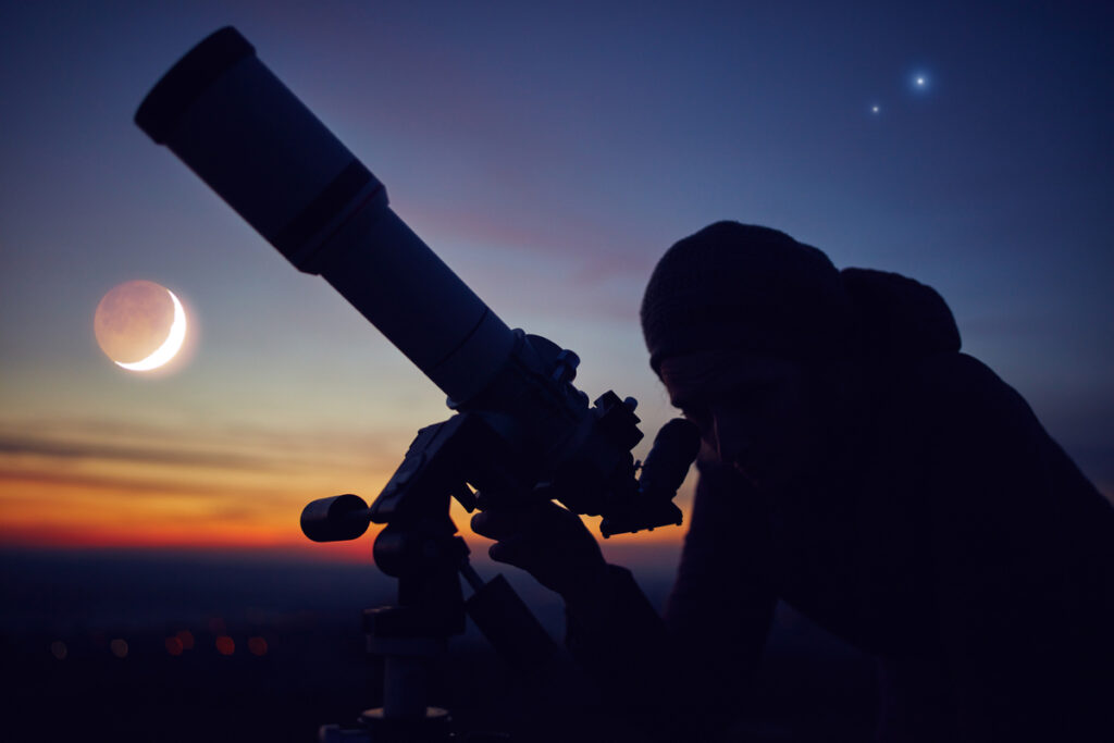 Силуэт человека, смотрящего в телескоп на закате