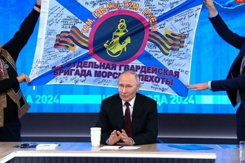 Владимир Путин и знамя 155-й бригады в ходе декабрьской прямой линии Скриншот из видео