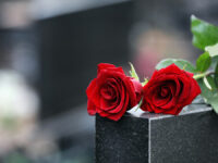 Red,Roses,On,Black,Granite,Tombstone,Outdoors,,Space,For,Text.