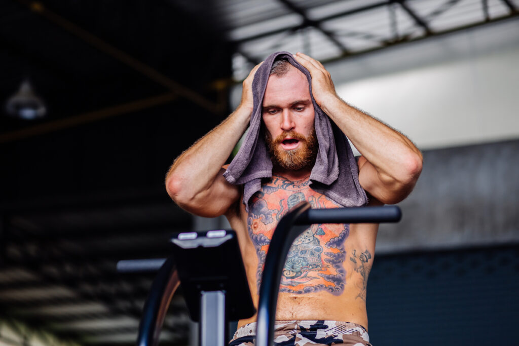 потный мужчина вытирается полотенцем