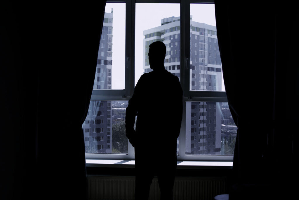 силуэт мужчины, разговаривающего по телефону на фоне окна