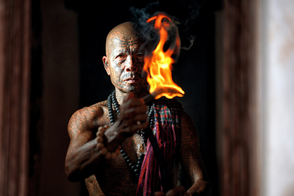 Портрет шамана с татуировками, позирующего с огнем