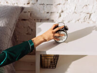 Рука тянется выключить будильник