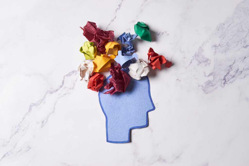 Скомканные бумажные листы лежат на вырезанном рисунке головы