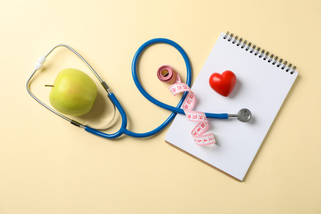 Стетоскоп, яблоко, блокнот, сердце и измерительная лента