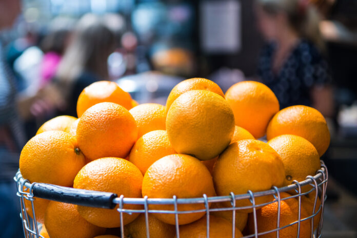 selective focus of pile of oranges in metal basket on blurred background Стопка апельсинов в металлической корзине