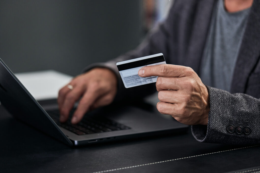 Мужчина, совершающий покупки в Интернете с помощью кредитной карты
