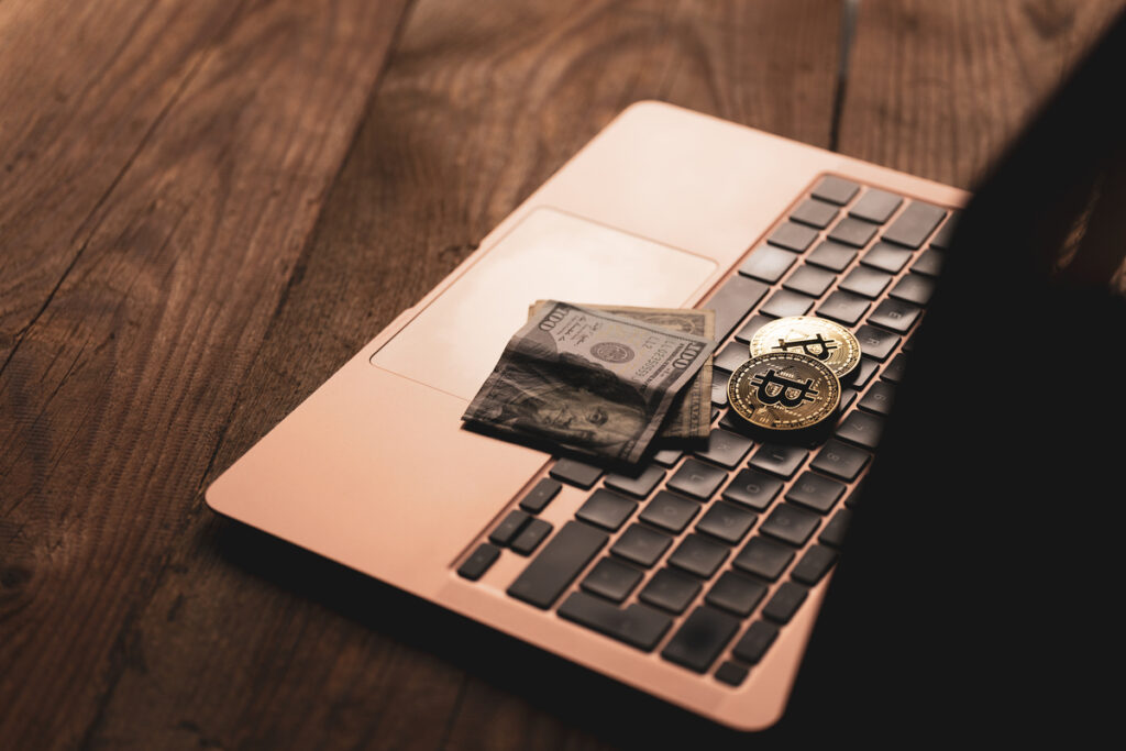 Золотая монета с символом биткойна и бумажные деньги
