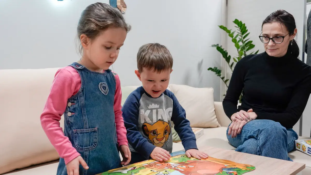 Воспитанники Центра содействия семейному воспитанию имени Ю. В. Никулина Марина и Тимофей изучают детскую развивающую игру вместе с воспитателем Мариной Ефимцевой. В центре создаются все условия для комфортного пребывания детей и их социализации