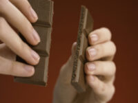 Ежедневные лайфхаки для продуктивности в холодное время года Крупный план рук, разбивающих плитку шоколада на две части