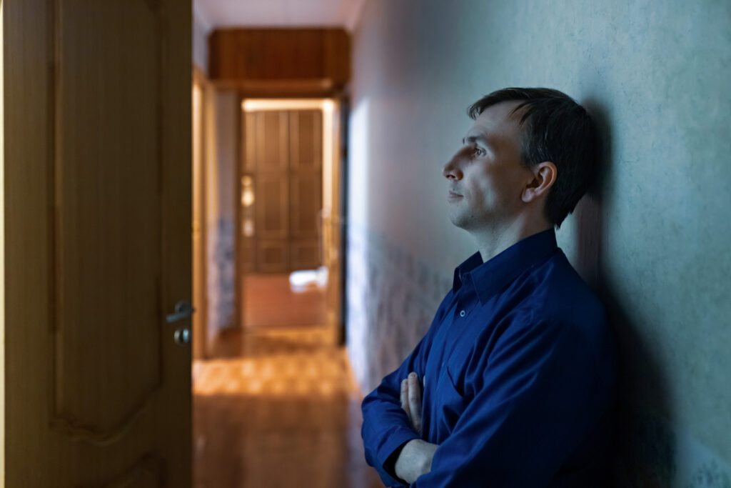 Молодой уставший мужчина сидит на полу в коридоре