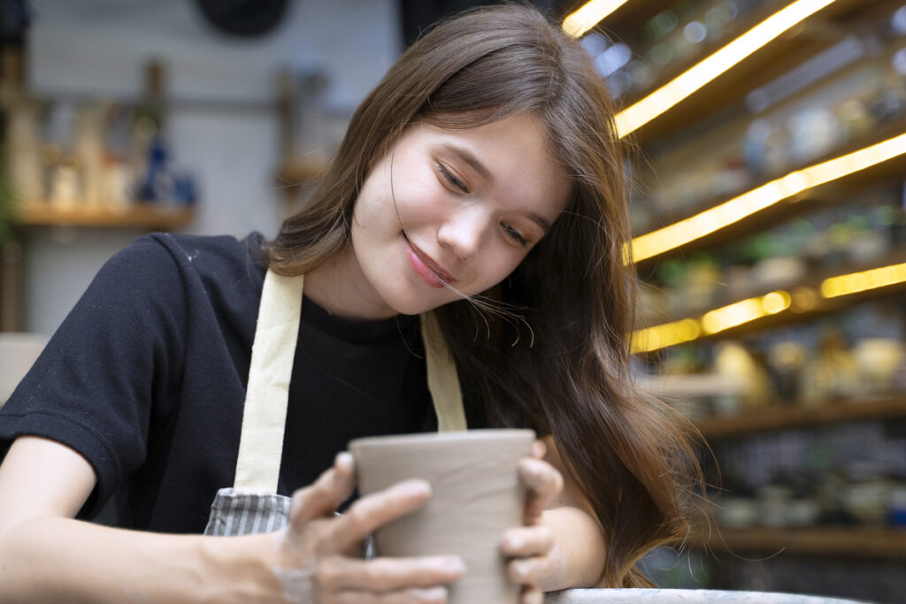 Девушка занимается изготовлением глиняной посуды