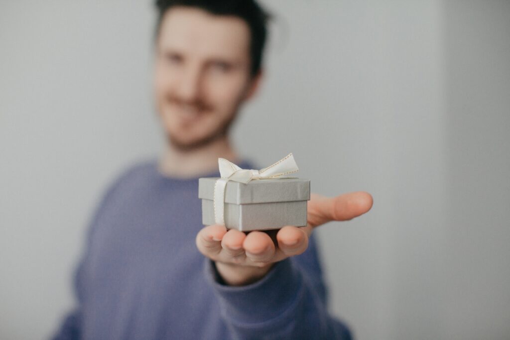Небольшая подарочная коробка с подарком в мужских руках