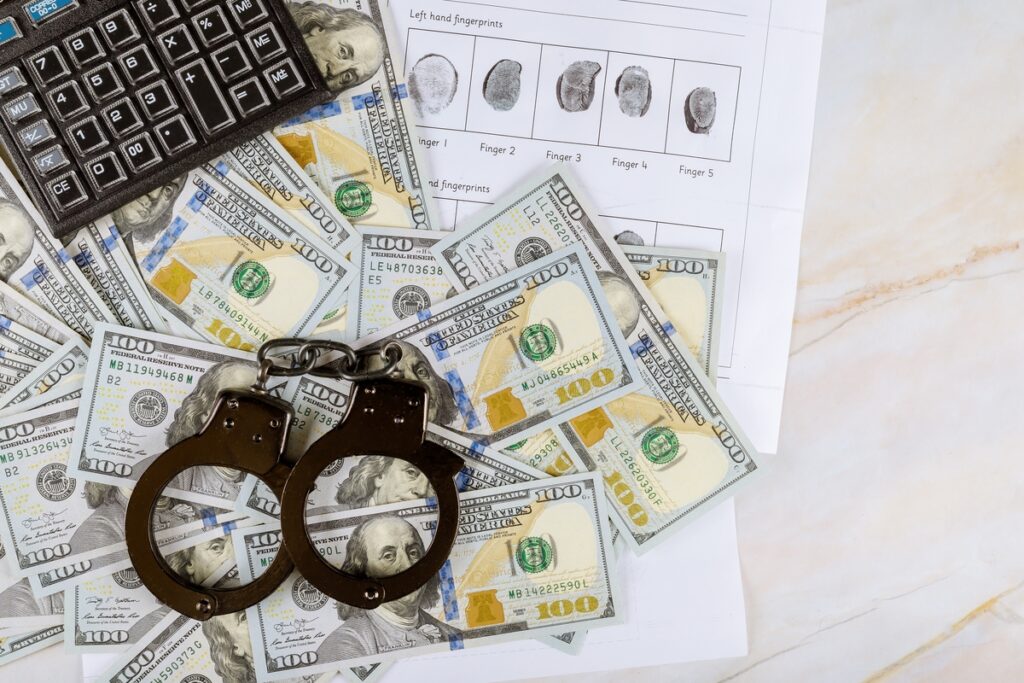 Handcuffs a criminal fingerprints on a calculator on US dollar banknotes - signaldaily наручники деньги отпечатки