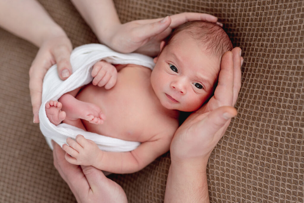 Awake newborn framed by parents hands - signaldaily новорожденный младенец