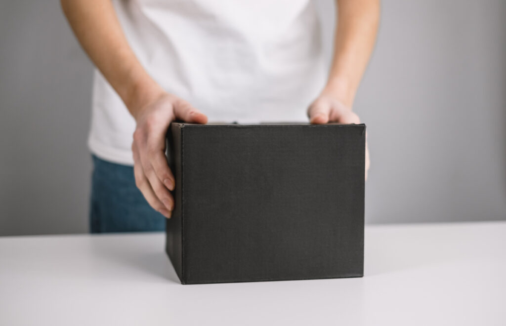 Person holding a black cardboard box the parcel in hands Delivery concept mock up - onlymainnews черный картонный ящик