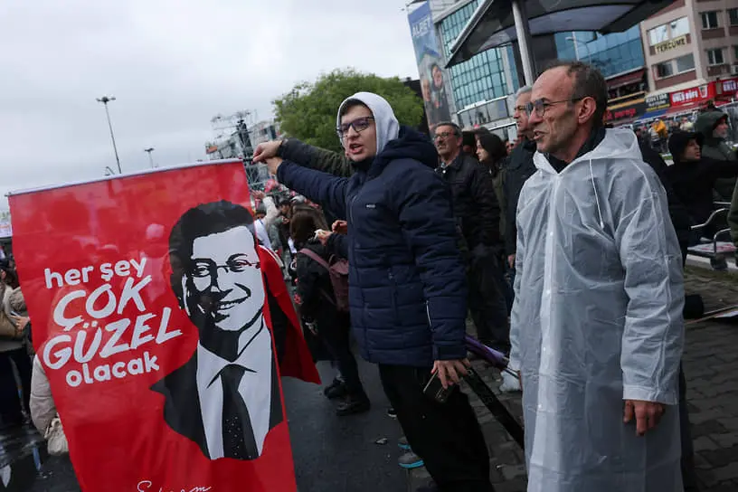 Люди с плакатом, где изображен арестованный в марте мэр Стамбула Экрем Имамоглу