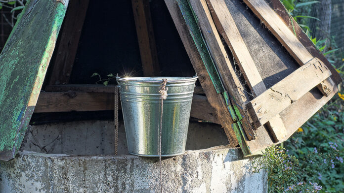 OneGrayMetalBucketOnARopeStandsOnAn