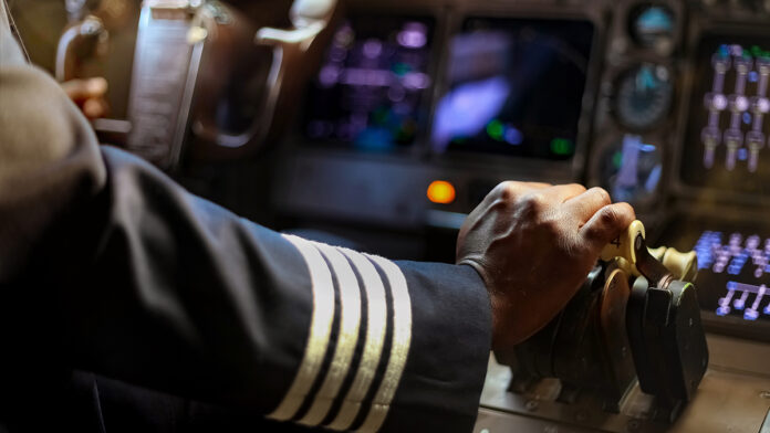 CroppedHandsOfAfricanPilotFlyingACommercialAirplaneCockpit