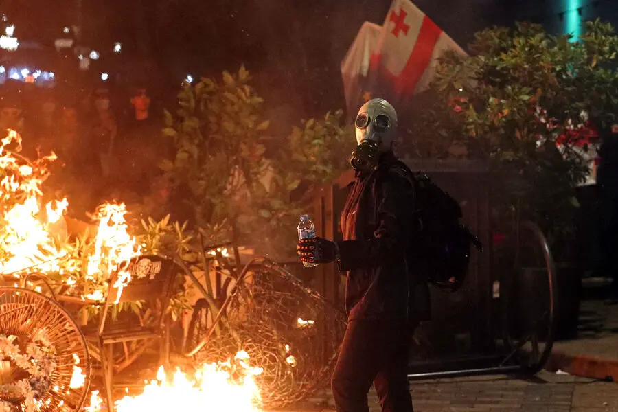Протестующий на фоне горящей баррикады во время митинга оппозиции в Тбилиси, 4 октября 2025 года