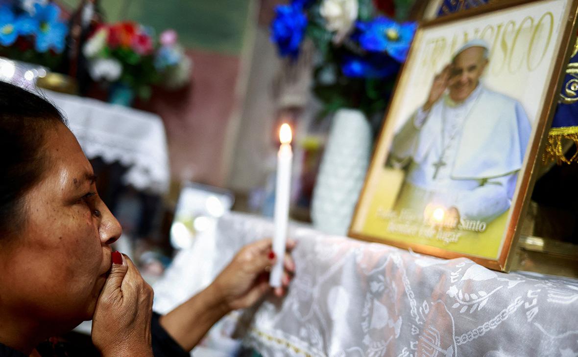 Прихожанка перед изображением папы римского Франциска в часовне Вирхен-де-Каакупе, в Буэнос-Айресе, Аргентина, 21 апреля 2025 года (Matias Baglietto / Reuters)