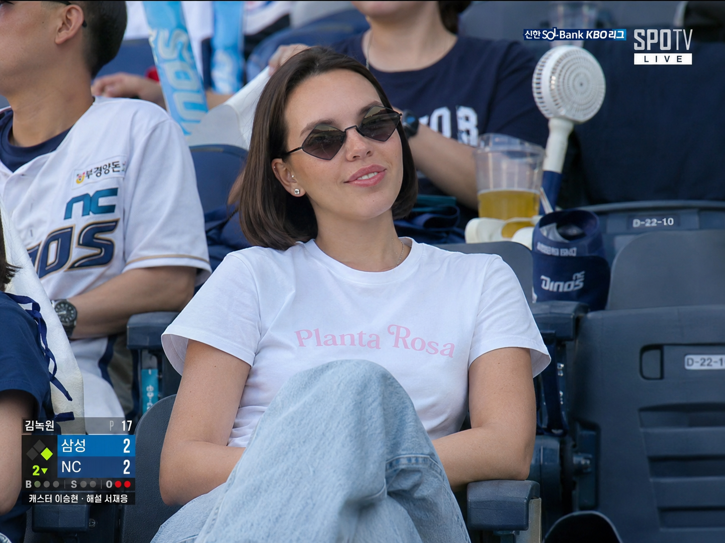 Realistic documentary-style sports broadcast frame captured in the spectator stands of a professi...