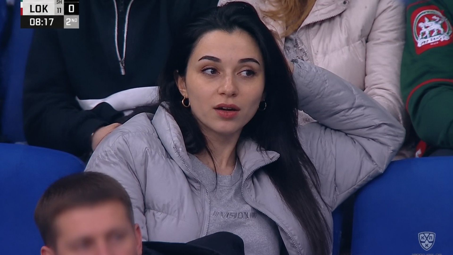 10-second realistic stadium broadcast animation. The woman stays centered and alive, with subtle ...