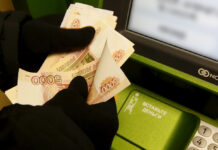 Житель Ростовской области потерял миллионы рублей из-за доверчивости к телефонным собеседникам Man counts Russian rouble banknotes while he uses ATM bank machine at branch of Sberbank in Krasnoyarsk