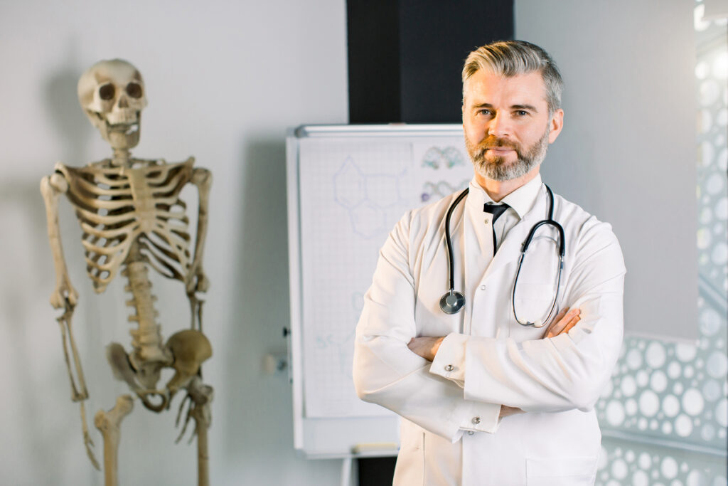врач улыбается на фоне скелета