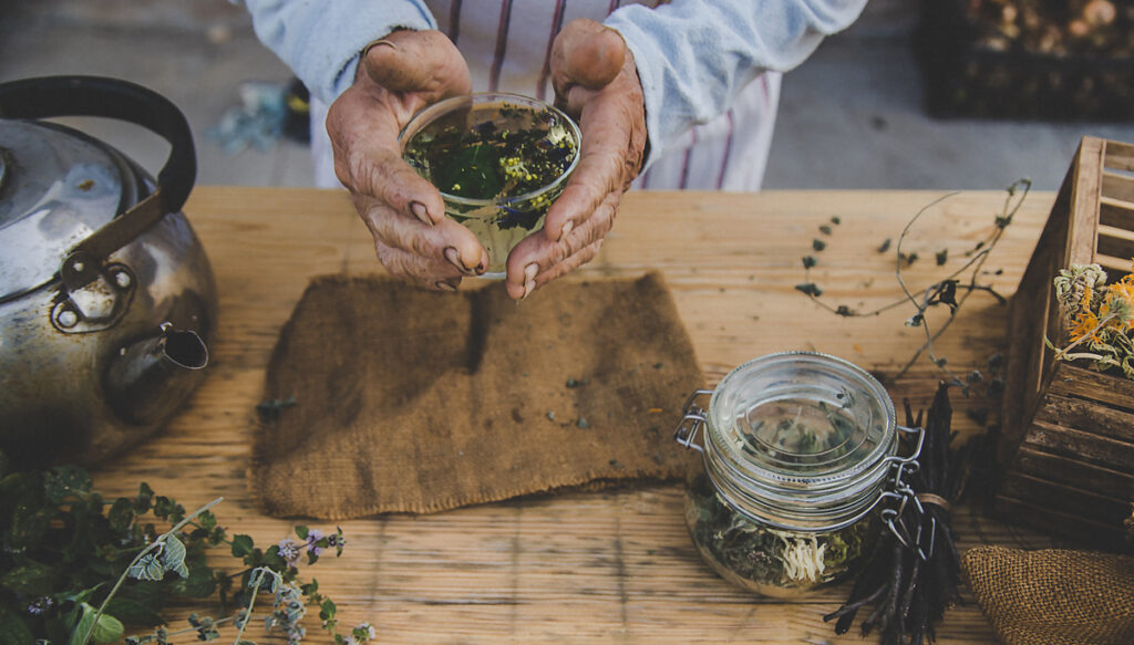 знахарь собирает настой из трав