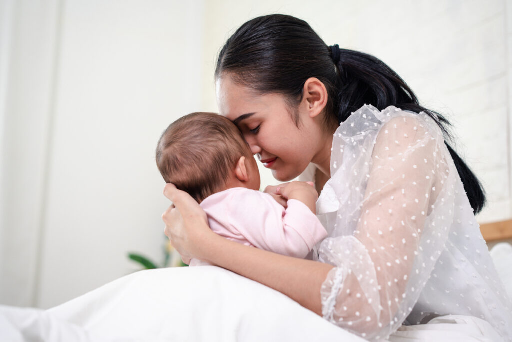 мама целует новорожденного ребенка