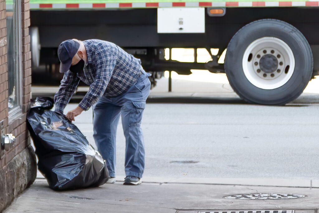 мужчина с черным мешком мусора