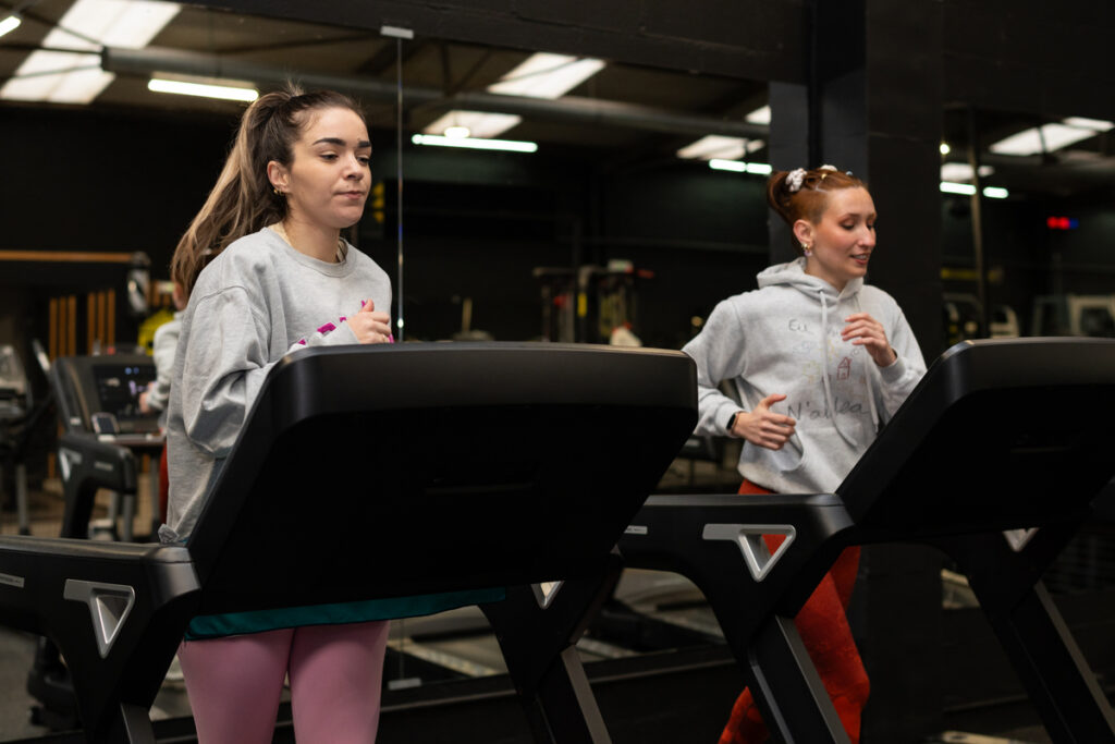 Две молодые женщины, бегающие на беговых дорожках